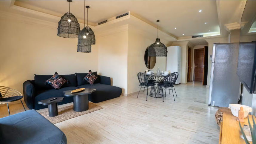 Salon lumineux avec canapé, coin repas et cuisine ouverte